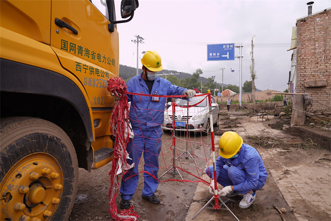 應(yīng)急保電人員正在為電源車裝設(shè)網(wǎng)圍欄。王國(guó)棟攝