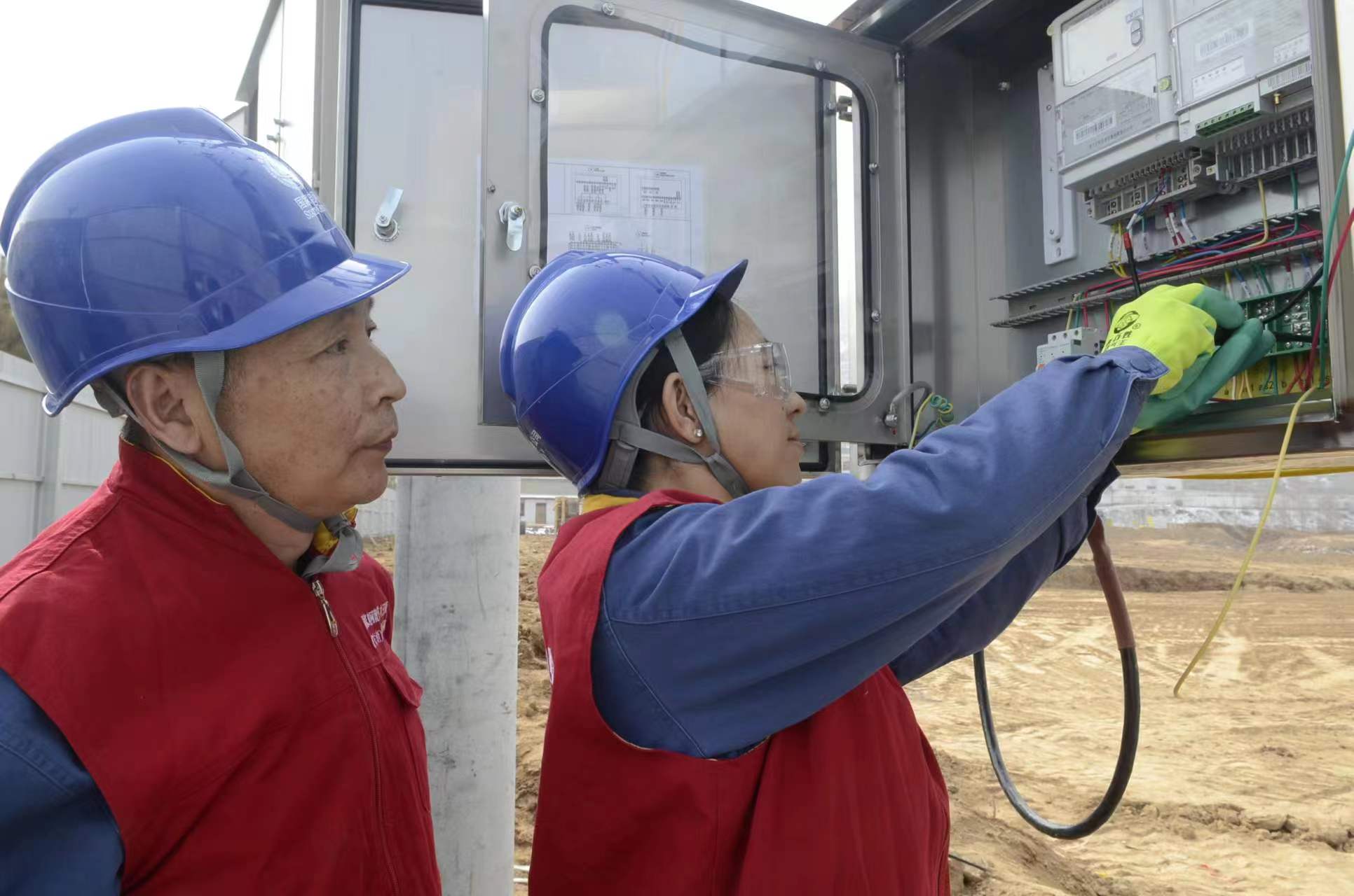 國家電網(wǎng)青海電力三江源（海東營銷）共產(chǎn)黨員服務(wù)隊(duì)隊(duì)長穆萍和隊(duì)員朱向陽進(jìn)行裝表接電作業(yè)，成功解決了青海省海東市民和縣川口鎮(zhèn)紅衛(wèi)村老年養(yǎng)護(hù)院建設(shè)工程施工用電問題。（馬彩虹 攝）
